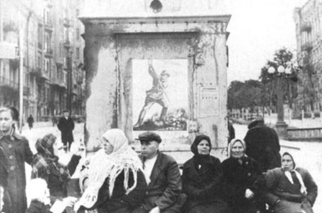 Киевляне на фоне советского агитационного плаката, бульвар Шевченко, сентябрь 1941 года