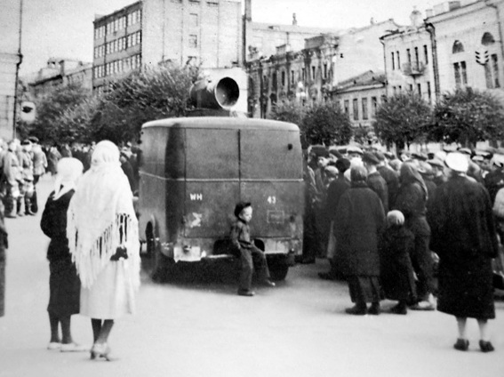Громкоговоритель на Крещатике. «Вокруг жизнь идет своим чередом. Базар торгует, радио кричит на улицах ненавистные немецкие танго, в зале управы концерт, посвященный Лысенко»